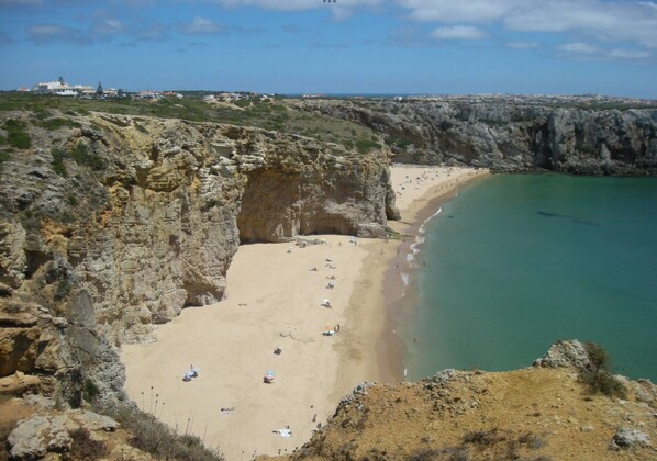 Uma praia costeira com falésias rochosas e uma faixa de areia.