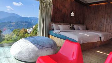 A bedroom with a large bed, wooden walls, a view of mountains, and a red chair.