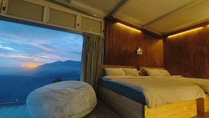 Un dormitorio con un ventanal grande, una cama y una pared de madera.
