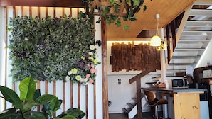 Un interior moderno con una escalera de madera, una zona de cocina con microondas y una sala de estar con una silla y una mesa.
