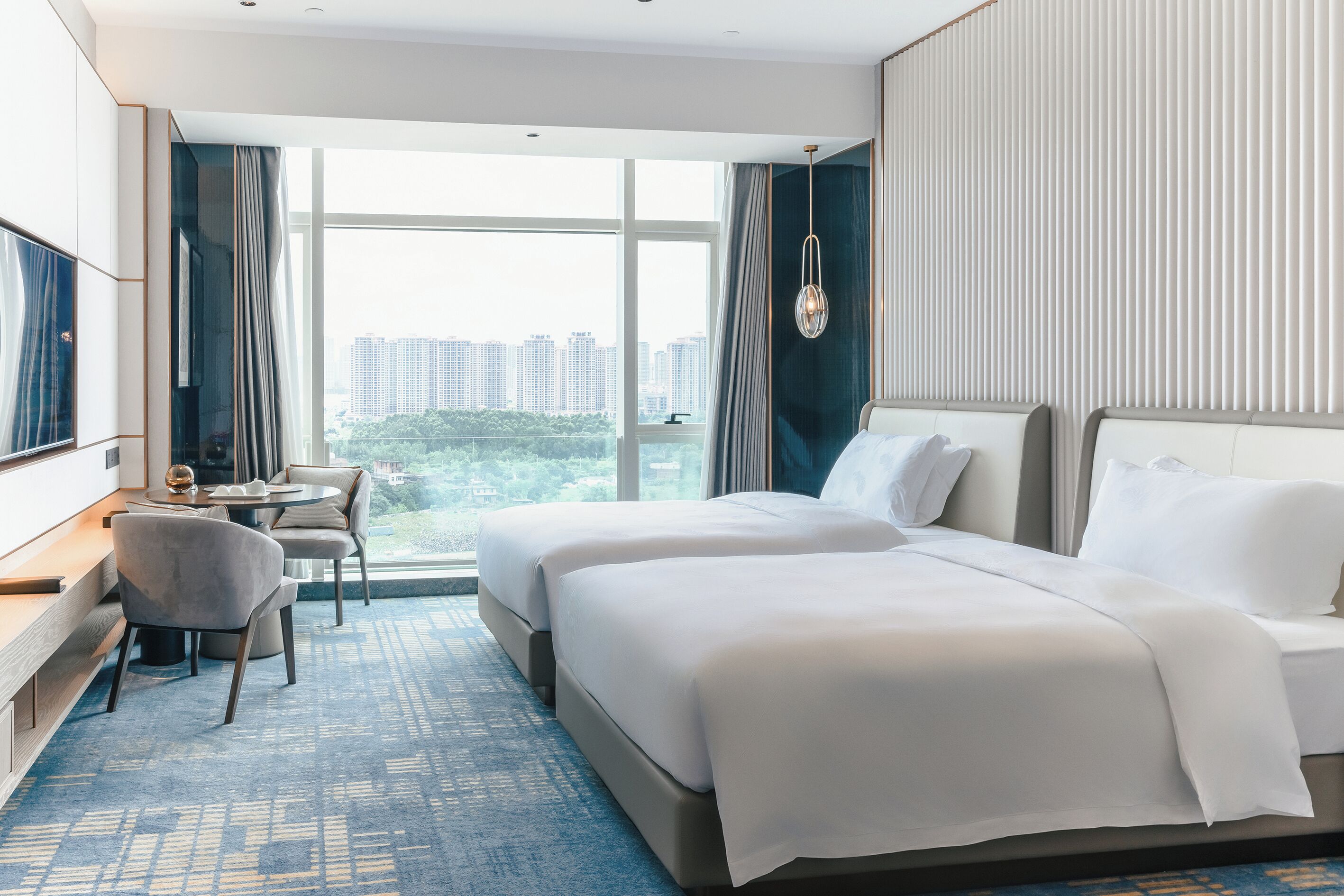 A hotel room with two beds, a desk, and a chair.