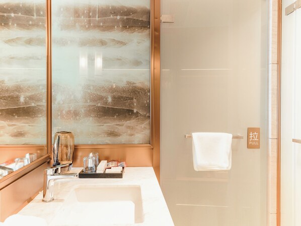 A modern bathroom with a large mirror, a glass shower enclosure, and a towel hanging on a door. - White Swan Hotel Zhangjiang (Zhanjiang)