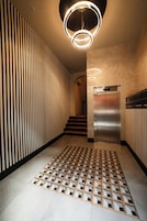 Un ascenseur moderne aux finitions métalliques, doté d’un sol à motifs et d’un mur avec des lattes verticales.