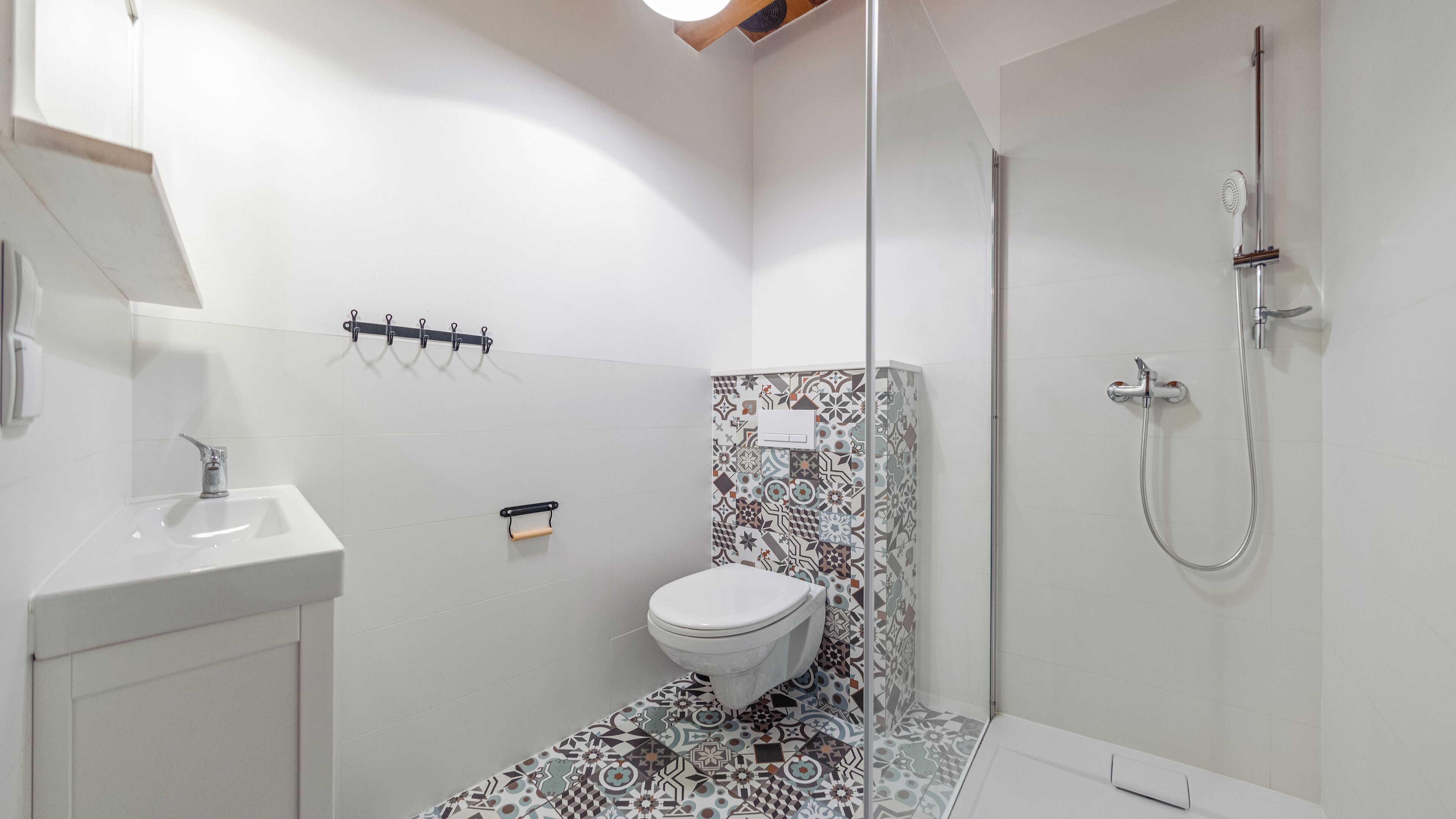 Un baño pequeño y moderno con un lavamanos blanco, un inodoro y una ducha.