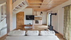 A modern living room with a sofa, a TV, a kitchen area, and a staircase.