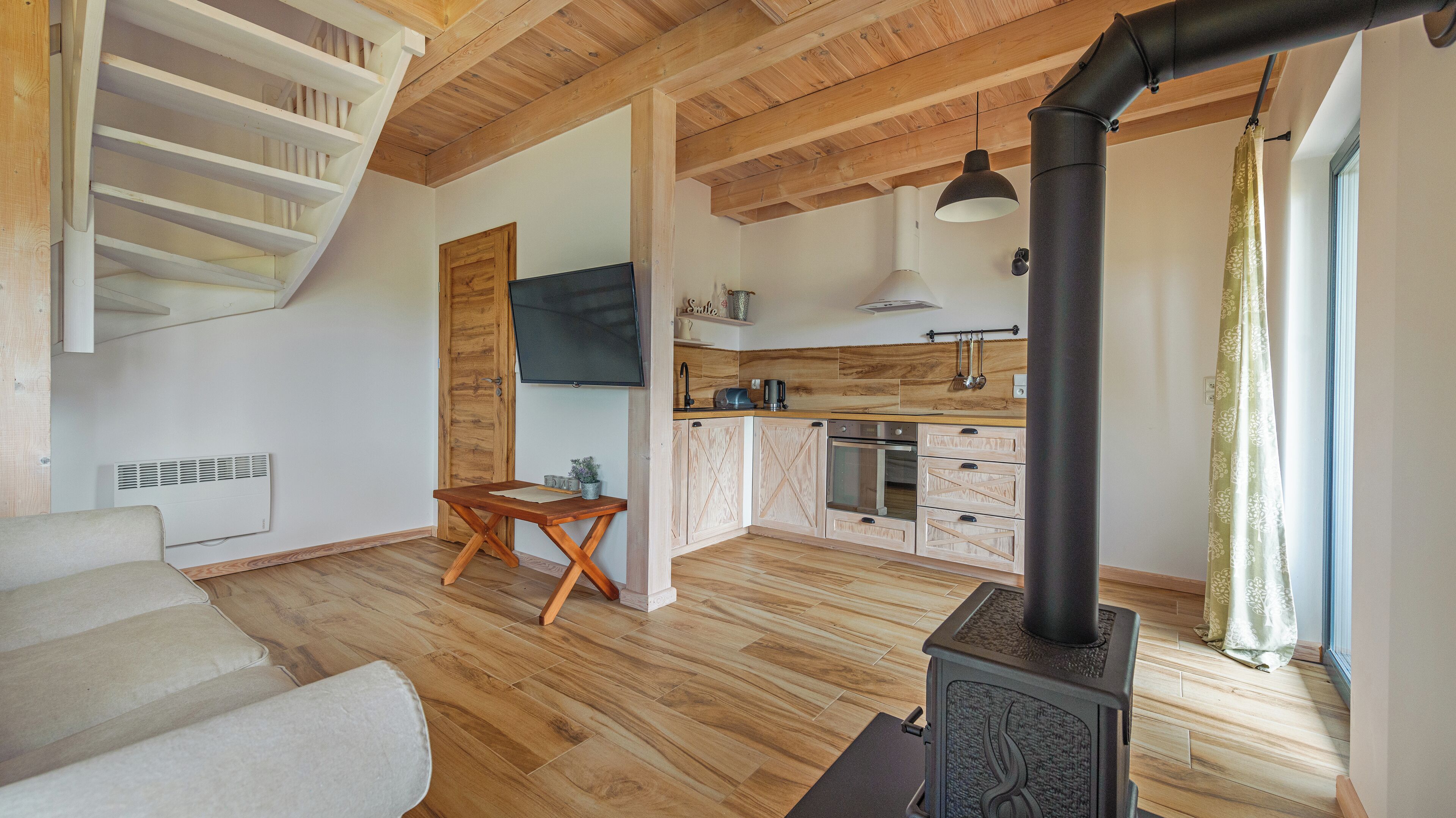 Una sala moderna con un sofá, una mesa de comedor de madera y una cocina con armarios de madera y una estufa negra.