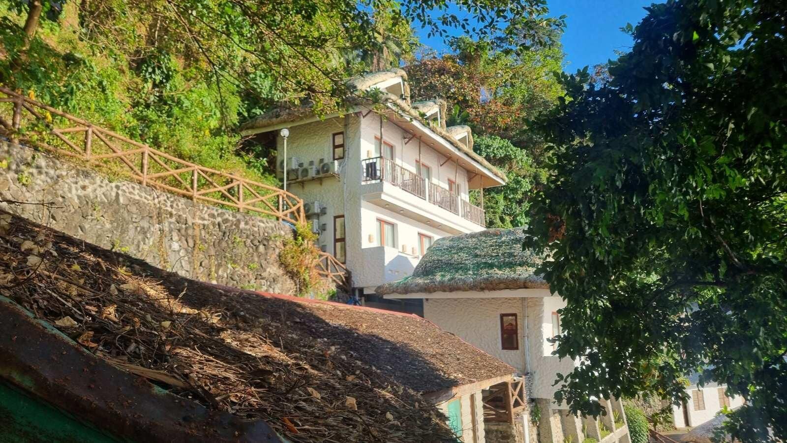 Un edificio de dos pisos con una escalera de piedra que lleva a una terraza de madera.