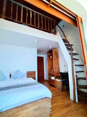 Een slaapkamer met een bed, een houten kledingkast en een trap.
