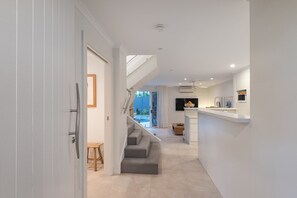 A modern interior with a staircase leading to a balcony, a kitchen area, and a dining space. - Little Cove Haven - Naousa 4 with Rooftop deck (Noosa)
