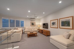A modern living room with a sofa set, a coffee table, a TV, and framed artwork on the walls. - Little Cove Haven - Naousa 4 with Rooftop deck (Noosa)