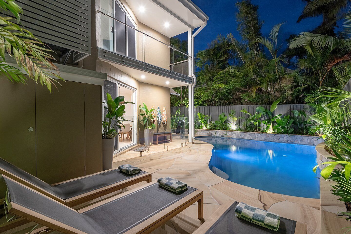 A modern outdoor pool area with lounge chairs and a covered seating area.