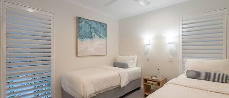 A bedroom with two beds, a ceiling fan, and a painting on the wall.