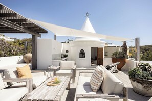 A rooftop terrace with outdoor seating, a small circular structure, and a decorative wind chime.