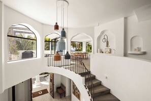 A spacious interior with a staircase leading to an upper level, large windows, and a dining area.