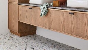 A bathroom with wooden cabinetry, two sinks, a mirror, and a towel rack.
