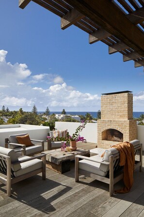 Eine Außenpatio mit Kamin aus Ziegelsteinen, Sitzgelegenheit und Blick auf das Meer.