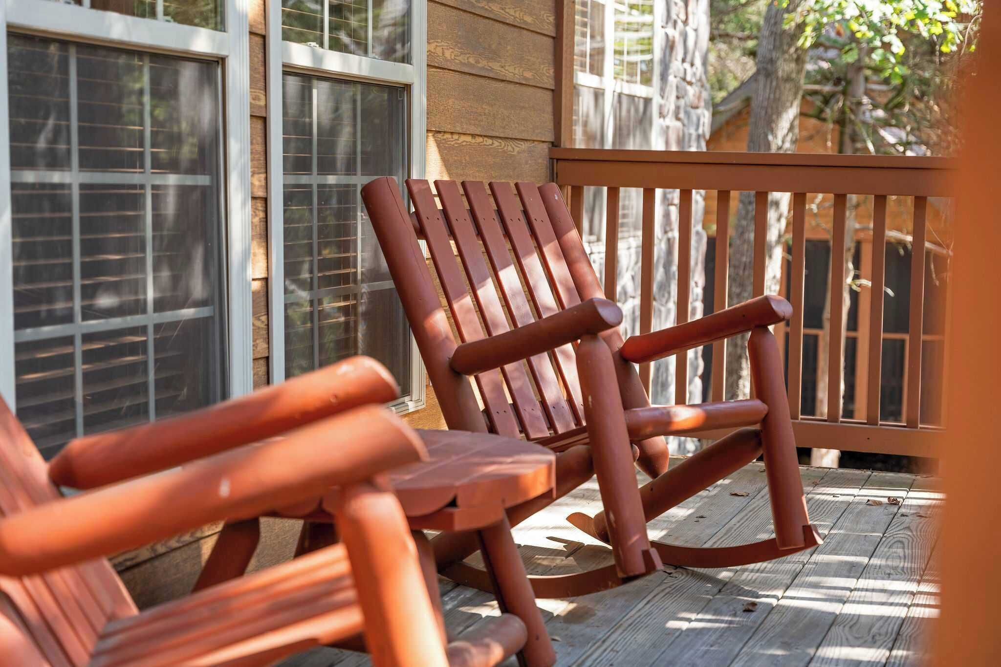 Une terrasse en bois avec une chaise berçante et une table.