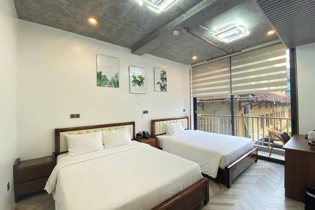 Quarto de hotel com duas camas, varanda e uma mesa de escritório.