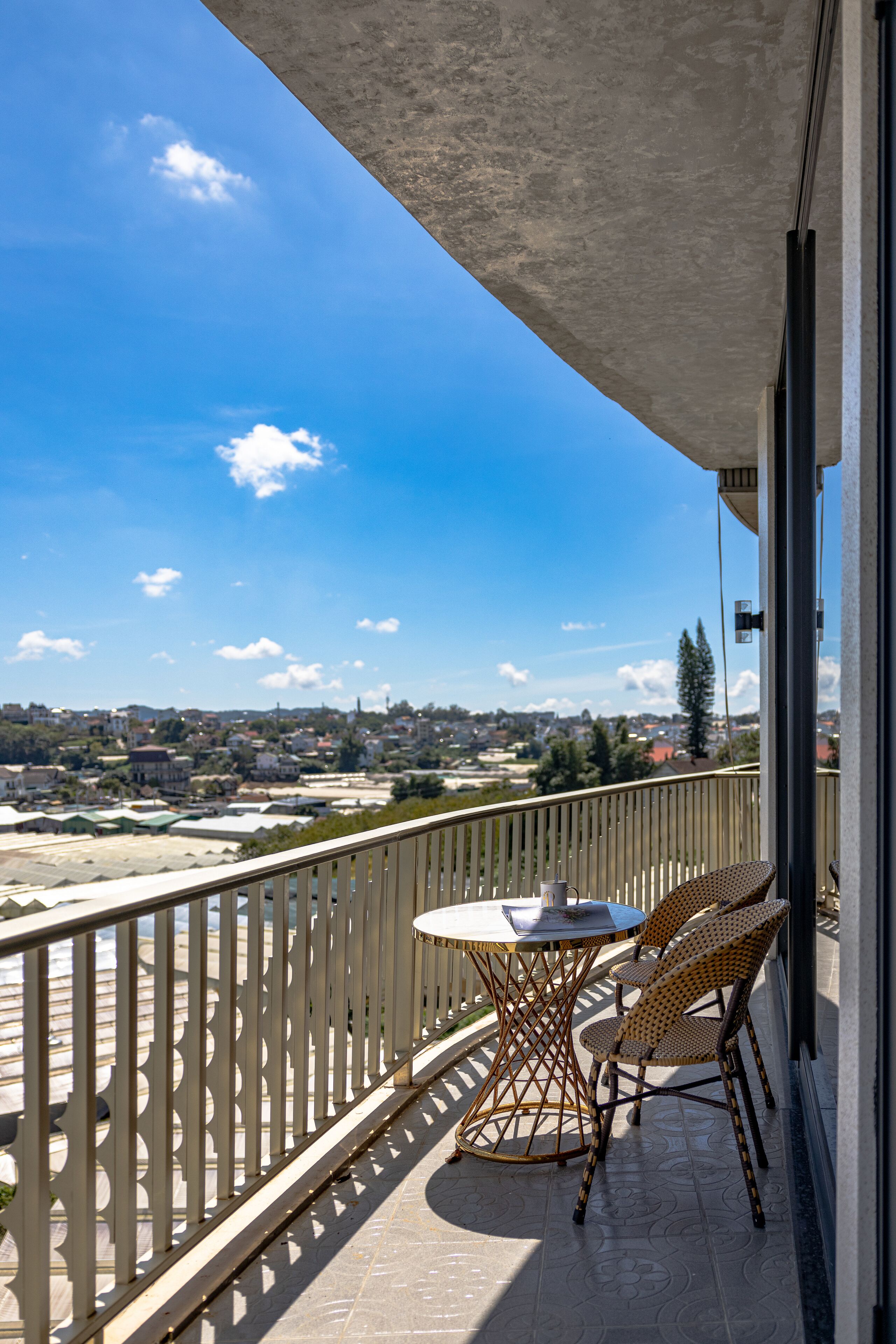 Varanda com mesa e cadeiras, vista para a cidade.