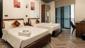 A hotel room with two beds, a desk, a chair, and a balcony with a view. - Phuc Hai Hotel Da Lat (Lang Biang - Da Lat)