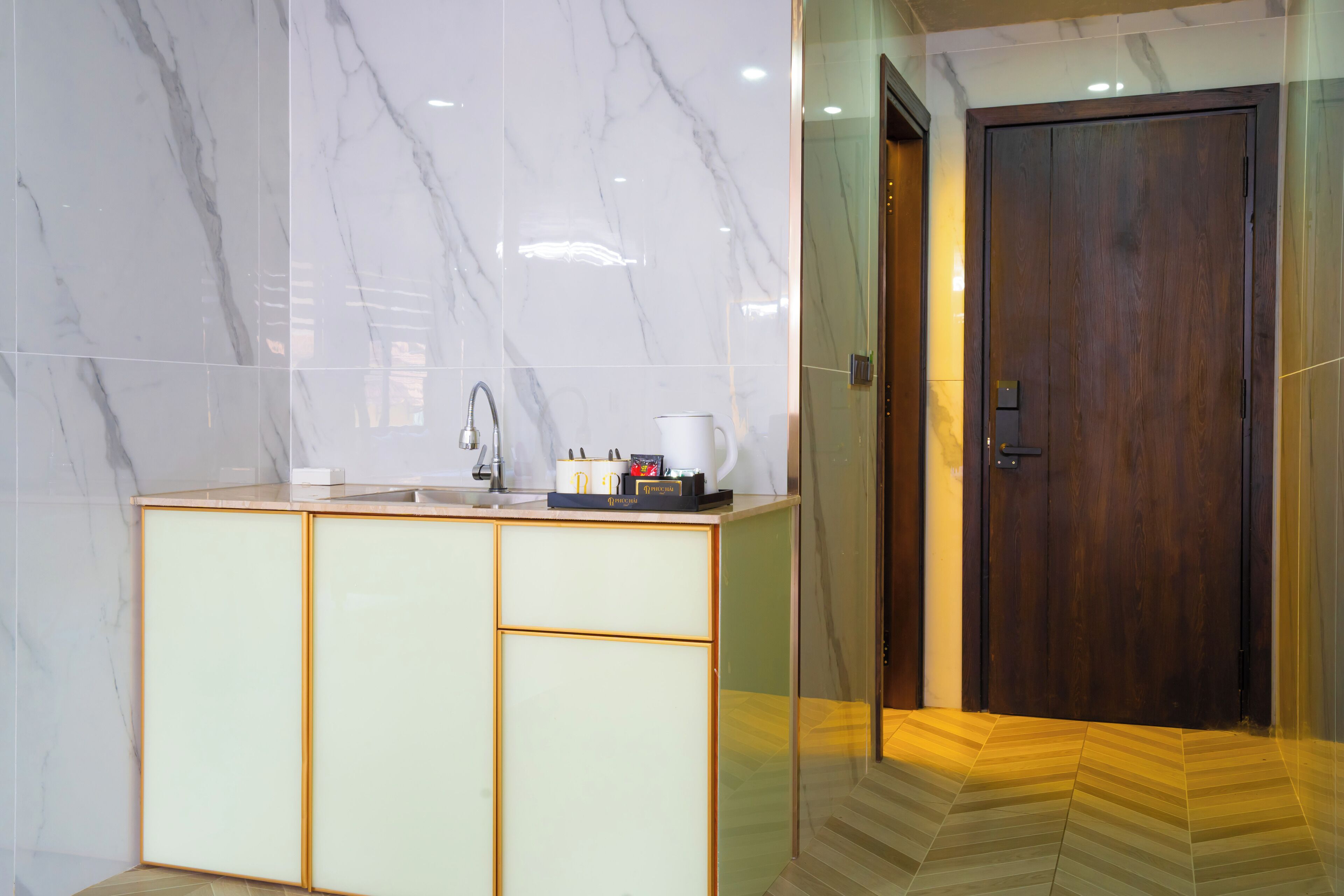 A modern bathroom with marble walls, a wooden door, and a small sink area with toiletries.