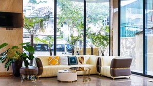 A modern lobby with a sofa set, a coffee table, and a large window offering a view of the street. - Phuc Hai Hotel Da Lat (Lang Biang - Da Lat)