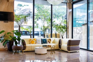 Um lobby moderno com um conjunto de sofás, uma mesa de centro e uma janela grande com vista para a rua.