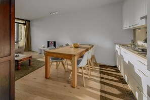 Eine moderne Küche mit weißen Schränken, einem Holztisch und einer Kücheninsel.