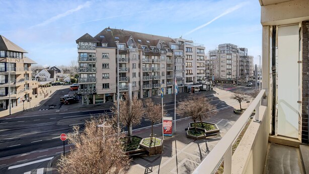 Un edificio residencial de varios pisos con balcones, estacionamiento y una señal de stop.