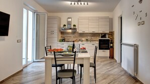 Une cuisine moderne avec des meubles en bois, une table à manger avec des chaises et un four encastré.