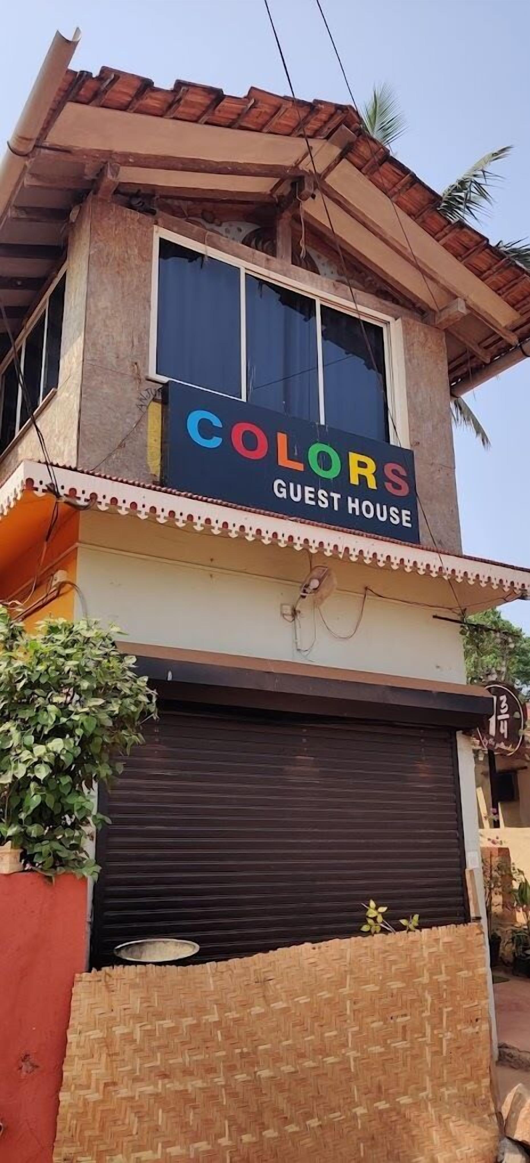 A guest house with a sign reading "COLORS GUEST HOUSE" above a closed garage door.