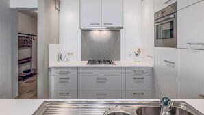 Una cocina moderna con electrodomésticos de acero inoxidable, muebles grises y horno empotrado.