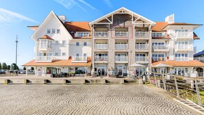 Un hôtel à plusieurs étages doté de balcons, d’un espace extérieur couvert et d’une place pavée.