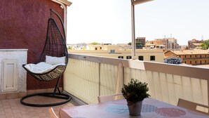 A balcony with a hanging chair, a table with a potted plant, and a view of the cityscape. - Via Casilina 161 in Rome (Rome)