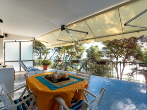 A covered outdoor seating area with a table set for two, surrounded by white chairs, and a potted plant. - il nido sul Mare by Interhome (Cervo)