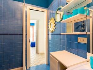 A bathroom with blue tiles, a white sink, a mirror, and a sun-shaped decoration. - il nido sul Mare by Interhome (Cervo)