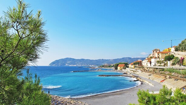 A coastal town with a rocky beach, clear blue sea, and buildings along the hillside. - il nido sul Mare by Interhome (Cervo)