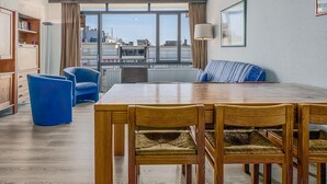 A modern living room with a wooden dining table, blue chairs, and a blue sofa. - 1 bedroom accommodation in Sint Idesbald (Sint Idesbald)