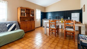 Un salon chaleureux avec un canapé, un meuble en bois et un coin repas comprenant des chaises et une table.