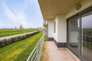 A balcony with a view of a green field and a road.