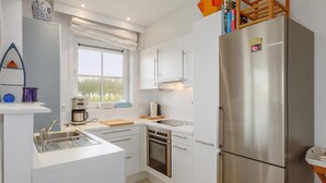 A modern kitchen with white cabinets, stainless steel appliances, a built-in oven, and a large refrigerator. - Zonnehaven II G 0002+G93 (NIEUWPOORT)