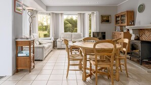 A modern kitchen with a dining area, large windows, and a fireplace.