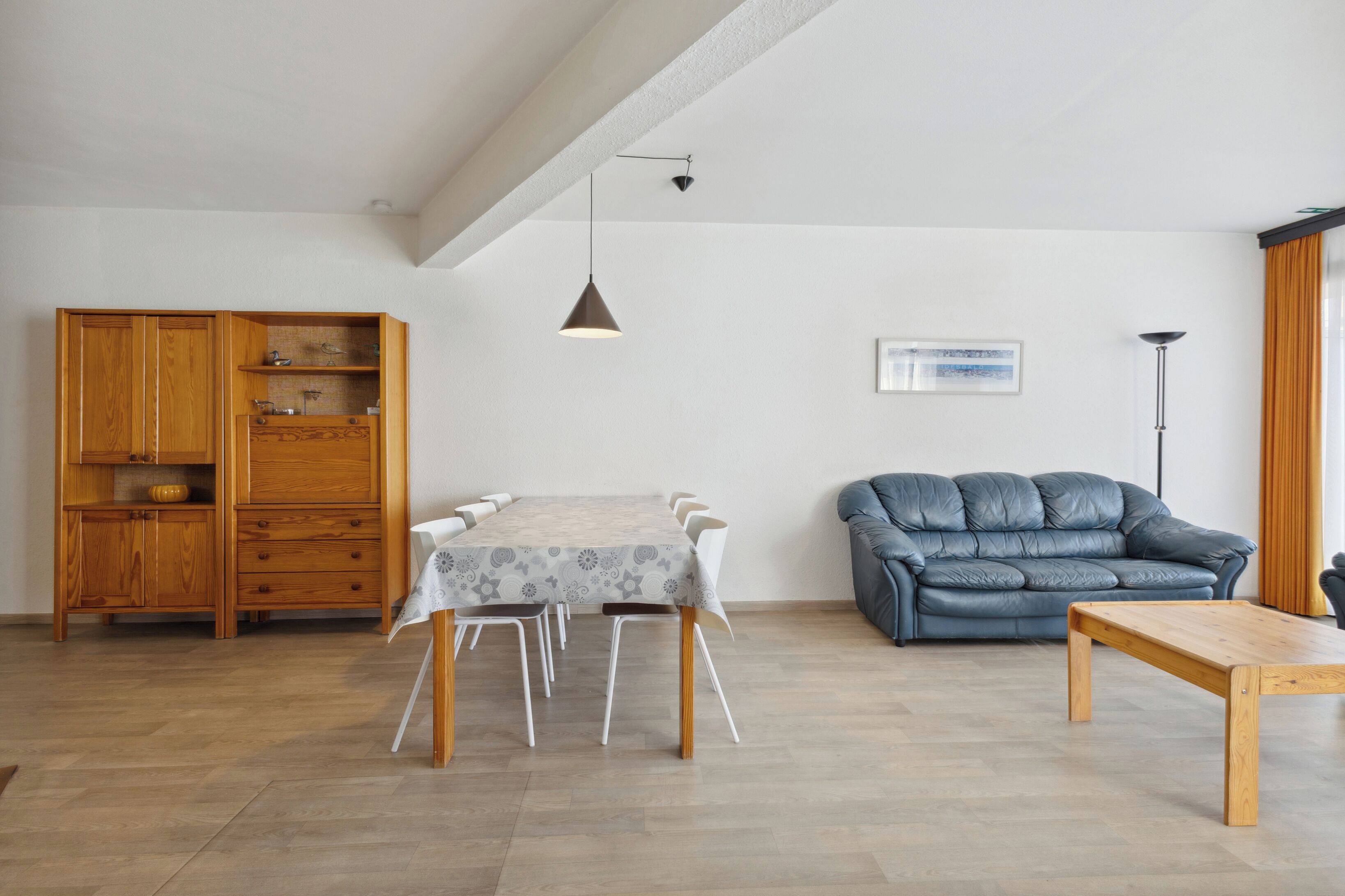 Ein Essbereich mit Tisch und Stühlen, einer blauen Ledersofa und einem Holzschrank.