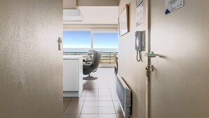 A hotel room with a view of the sea, a chair, a desk, and a radiator.