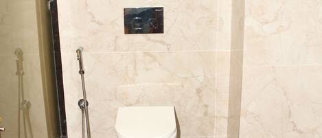 A bathroom with a toilet, a shower, and a glass-enclosed shower area.