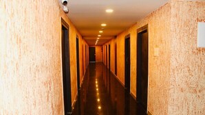 A long, narrow hotel corridor with doors on both sides, a shiny reflective floor, and recessed ceiling lights. - SAS SQUARE (Tiruchirappalli)