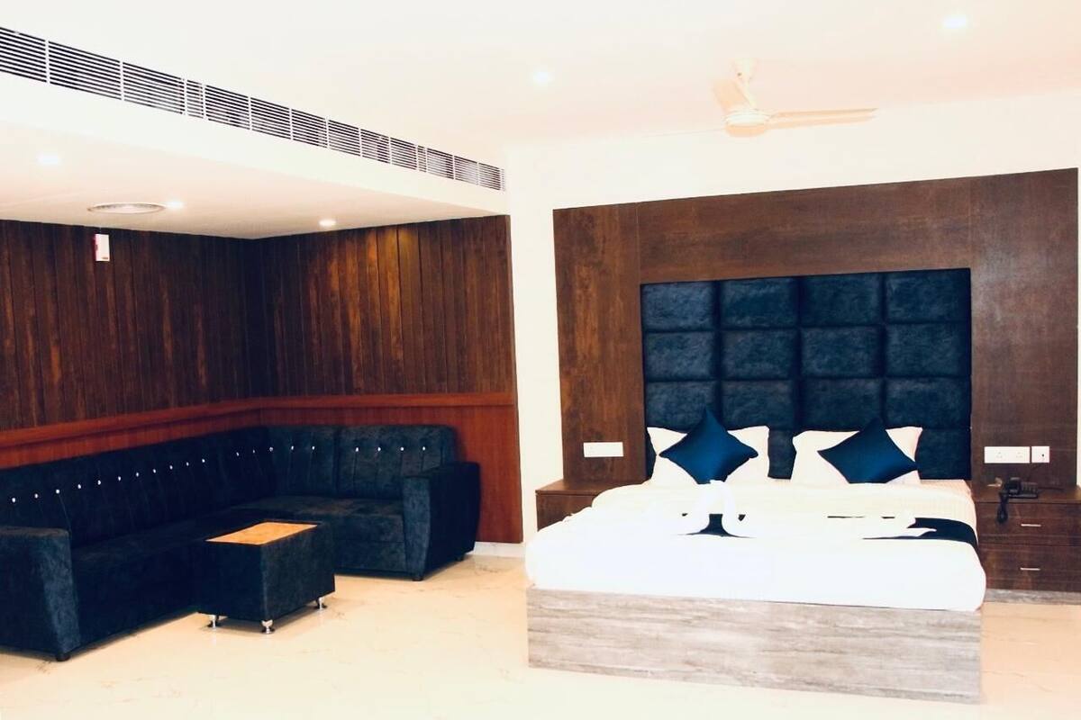 Ein modernes Schlafzimmer mit einem großen Bett, einem dunkelgrauen Sofa und einem kleinen Tisch.