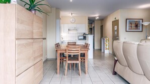 A modern kitchen with a dining table and chairs, a sofa, and a plant. - 2 bedroom accommodation in Oostduinkerke (Oostduinkerke)