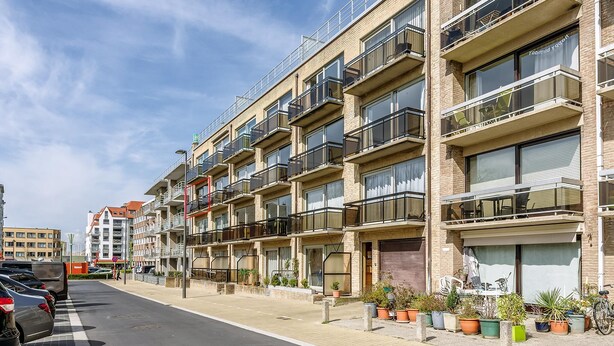 A multi-story residential building with balconies, a parking area, and potted plants. - 2 bedroom accommodation in Oostduinkerke (Oostduinkerke)