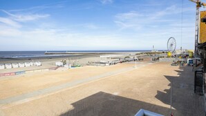 A beach with a pier, a Ferris wheel, and a construction crane.